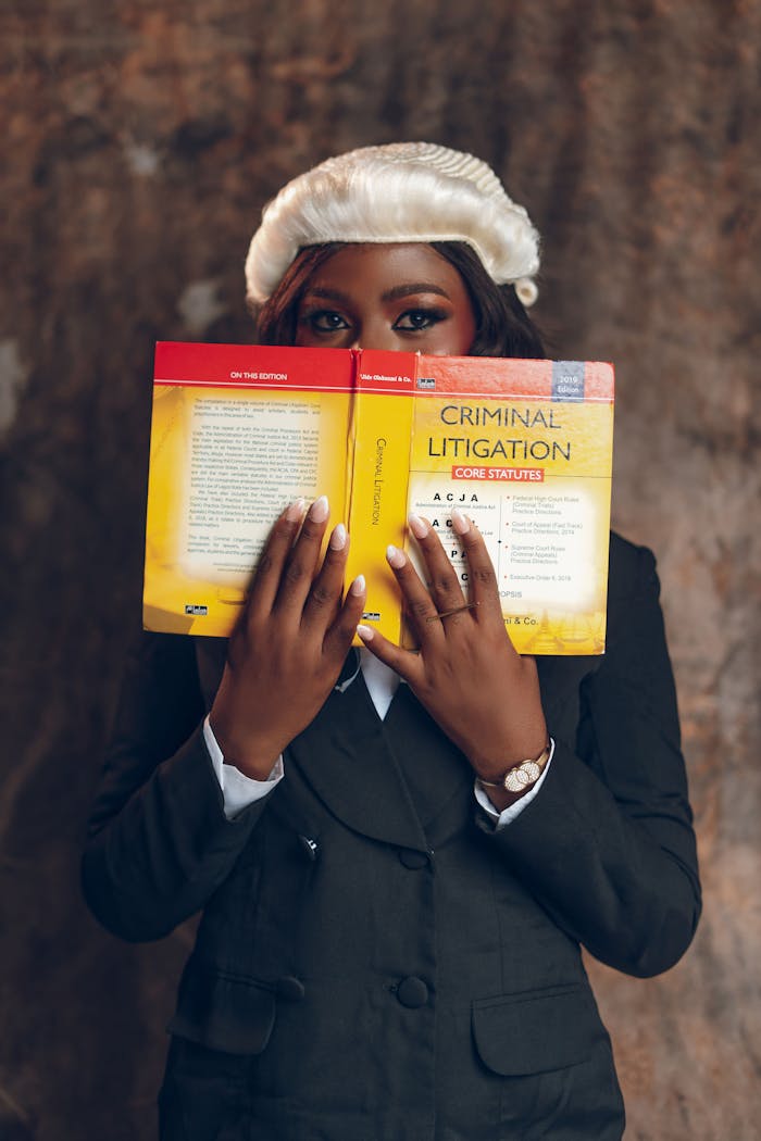 A young lawyer in formal attire reads a criminal litigation book, showcasing professionalism.