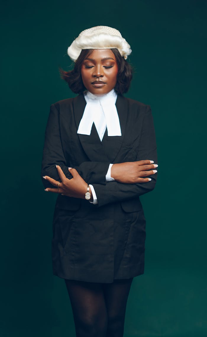 Portrait of a confident female lawyer in traditional legal attire with eyes closed.